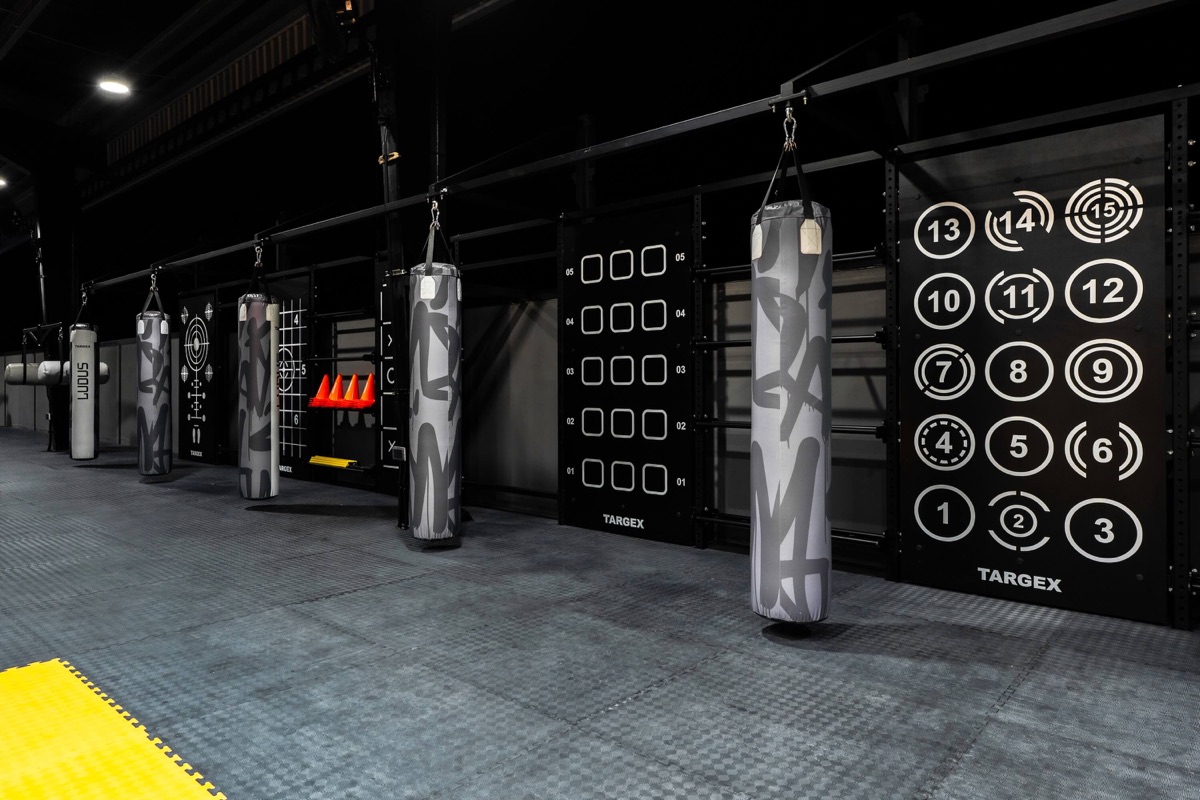 A row of heavy bags beside the target wall at LUDUS