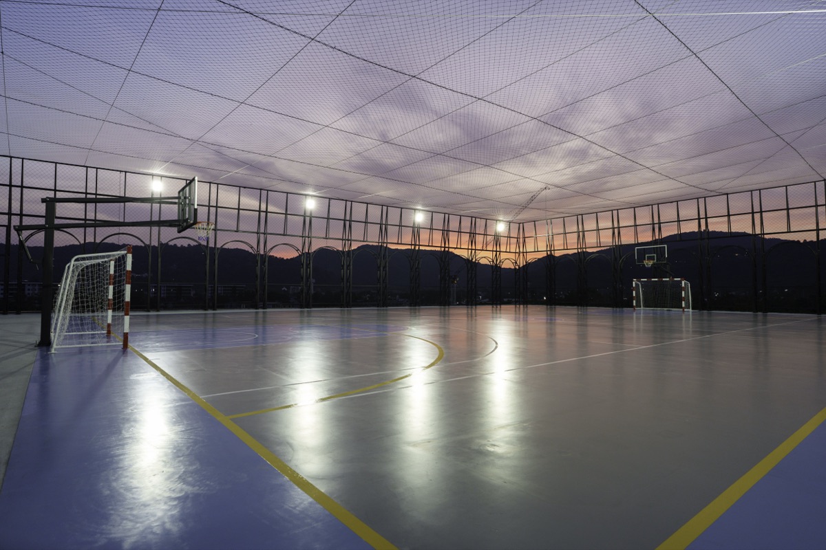 The LUDUS rooftop sports court at dusk, with the hills behind